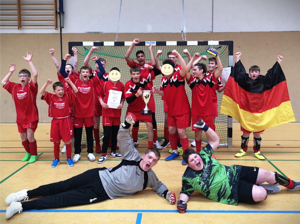 Die siegreiche Mannschaft des Fußballturniers jubelt mit Pokal und Urkunde.