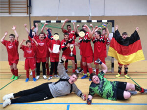 Die siegreiche Mannschaft des Fußballturniers jubelt mit Pokal und Urkunde.